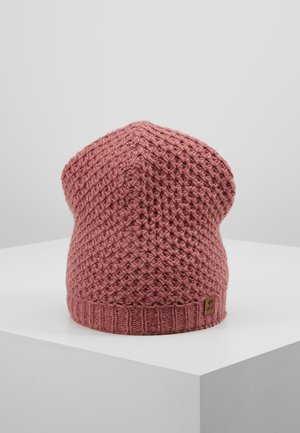 Bonnet en tricot rose avec une texture à motif gaufré, bord-côtes et une petite étiquette logo marron sur un socle blanc.