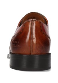Zapato de vestir de cuero marrón visto desde la parte trasera, con detalles de costura y una suela negra, con el nombre de la marca grabado en el talón.