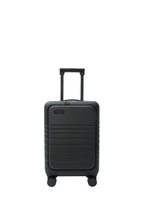 Kompakter schwarzer Hartschalenkoffer mit horizontalen Rillen, vier Spinner-Rädern und einem ausziehbaren Teleskopgriff.