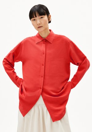 Chemise rouge vif à manches longues avec boutonnage, fabriquée en tissu texturé. Elle possède un col et une poche poitrine. Ourlet courbé.