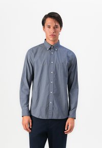 Camisa de botones navy con un pequeño patr�ón de lunares blancos, mangas largas, cuello punto y un logo sutil de la marca en el pecho.