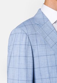 Jasnoniebieska marynarka wykonana z fakturowanej tkaniny w kratę. Posiada klapy z ząbkami oraz dopasowany krój.