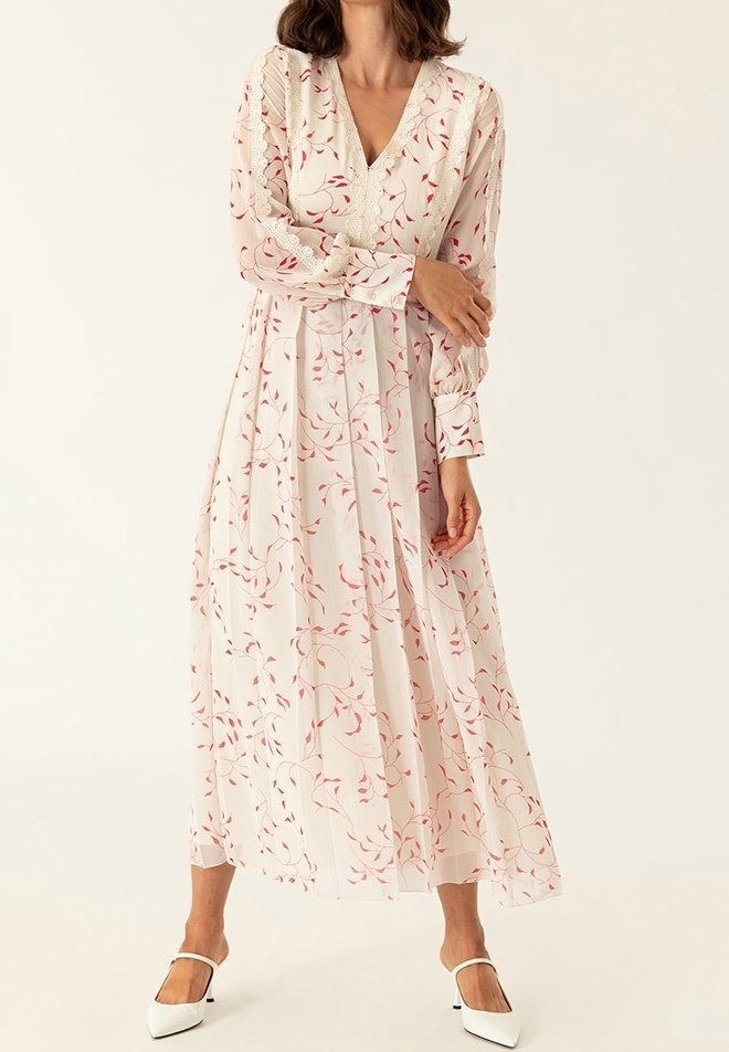 Vestido de manga larga y escote en V, hecho de una tela ligera y transparente con patrones de hojas rosas sobre un fondo blanco. Presenta una cintura fruncida y una silueta fluida.