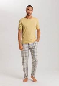 Lichtgele, kortemouw, katoenen t-shirt gecombineerd met katoenen pyjamabroek met een ruitpatroon in blauwtinten, grijs en beige. Strakke pasvorm met een comfortabele fit.