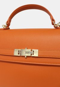 Sac à main en cuir orange avec un design structuré, doté d'une fermeture à cliquet en or portant l'étiquette "Valentino" et d'une finition lisse et texturée.