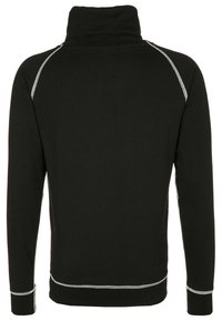Suéter negro con cuello alto, con detalles de costura blanca a lo largo de las costuras. Tejido suave con mangas largas y un diseño ajustado.