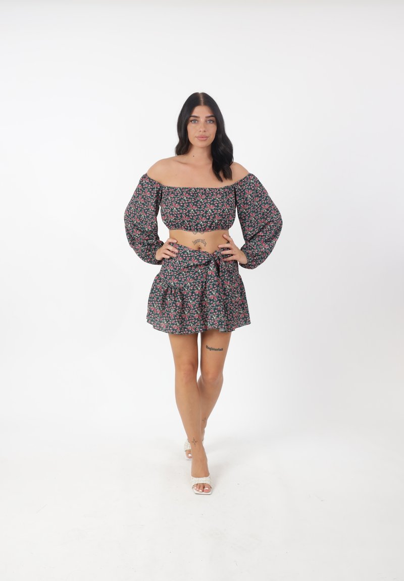 Blommig crop top med elastisk design off-shoulder, i kombination med en matchande utsvängd kjol med knytning vid midjan, i svart och rosa.