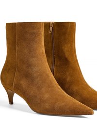 Bottines en daim marron avec un embout pointu et un talon kitten élancé, dotées d'une fermeture à glissière sur le côté pour un enfilage facile. Texture lisse et design sans couture.