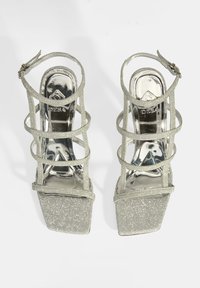 Silberne Glitzer-High-Heel-Sandalen mit einer klobigen Plattform, offener Zehenpartie und crisscross Riemen-Design. Mit einer glänzenden, metallischen Einlegesohle.