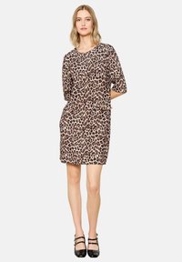 Kleid mit Leopardenmuster, kurzen Ärmeln, Taschen und entspannter Passform. Der Stoff hat eine glatte Textur und erscheint weich und leicht.