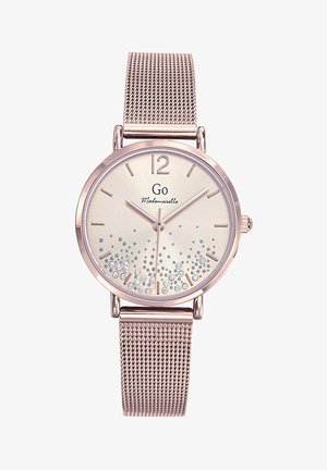 Montre ronde avec un bracelet en maille métallique en or rose, présentant un cadran crème clair orné de pierres précieuses et de chiffres arabes aux positions 12 et 6.