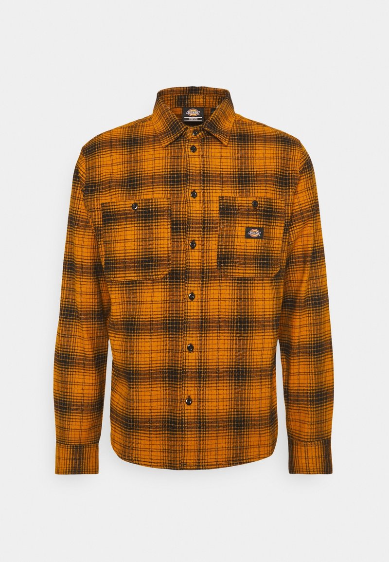 Chemise à manches longues orange et noire à carreaux avec des boutons noirs et deux poches poitrine devant, dont une avec un petit écusson logo.