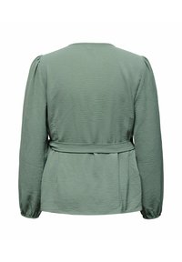 Grønn teksturert bluse med lange ermer, rund halslinning og knyting i midjen. Har puffede skuldre og en lett avslappet passform.