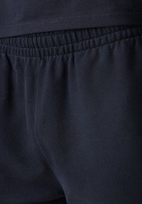 Sorte joggebukser med elastisk midjebånd, myk bomullsblanding, glatt tekstur og rett ben design.