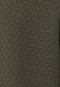 Olivgrön texturerad tyg med ett subtilt rutmönster, mjukt vid beröring. Jämn färgdistribution utan synlig hårdvara eller accenter.