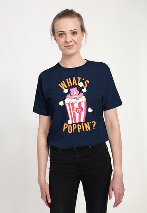 Navyblaues Baumwoll-T-Shirt mit einem bunten Grafikdesign eines Bären in einem Popcorn-Eimer, mit dem Text "WAS GEHT AB?" in verspielten Schriftarten.