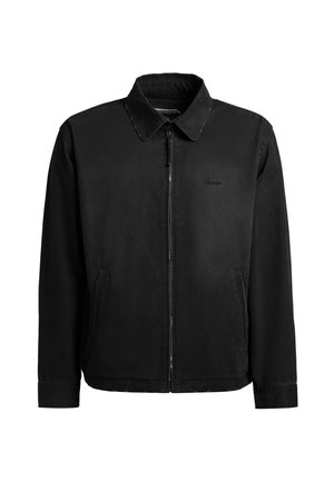 Giacca nera con cerniera, collo, maniche lunghe, tasche laterali e logo discreto sul petto sinistro, mostrata su sfondo bianco uniforme.