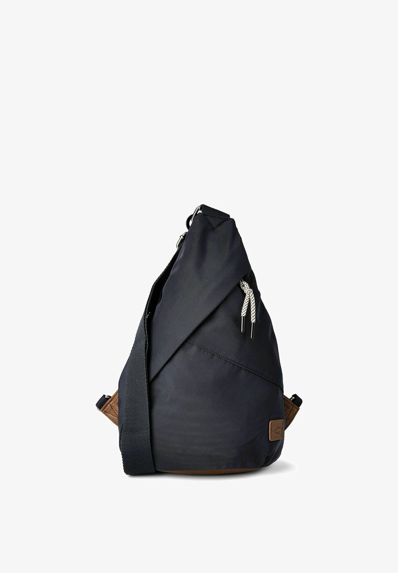 Schwarzer Sling-Rucksack mit verstellbarem Schulterriemen, vorderer Reißverschlusstasche und braunem Leder-Logo-Aufnäher an der unteren Ecke.