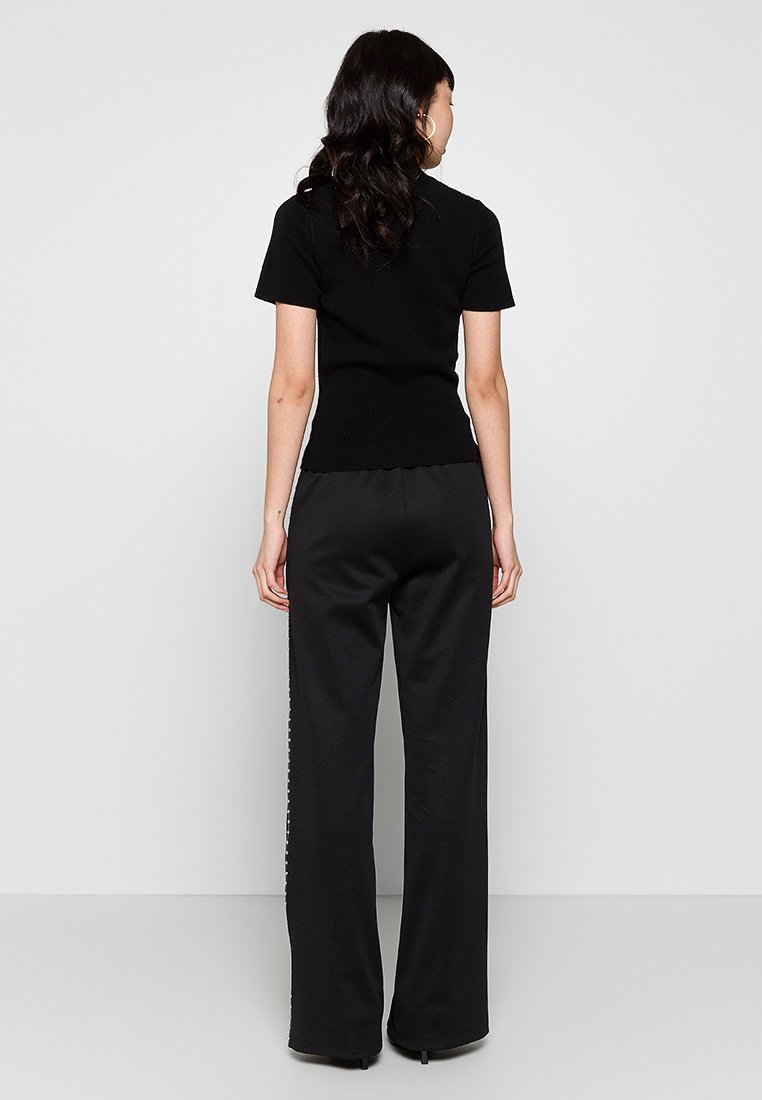 Top corto aderente nero a maniche corte con texture a coste abbinato a pantaloni neri a gamba larga caratterizzati da una rifinitura con motivo verticale lungo il lato.