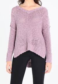 Přes oversized v-neck pletený svetr ve světle fialové barvě s volným vzorem, asymetrickým lemem a žebrovanými akcenty na rukávech a spodním lemu.