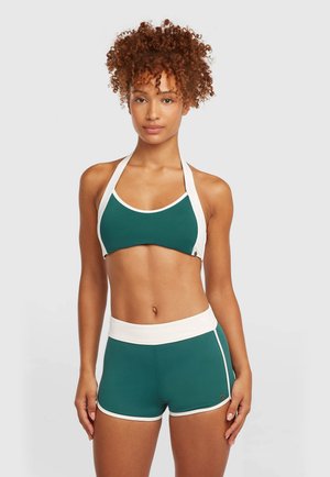 Sinine-sinine spordirinnahoidja valge ääristusega ja halter-kaelusega; sobivad kõrge vöökohaga lühikesed püksid valge vöörihma ja ääristusega; veniv ja istuv materjal.