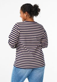 T-shirt à manches longues rayé en marine et beige, texture côtelée, col rond, coupe décontractée, associé à un jean en denim bleu clair.