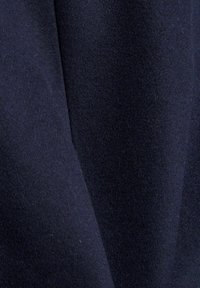 Marineblauwe stof met een zachte, gestructureerde afwerking, met subtiele variaties in tint en diepte. Het materiaal lijkt dik en warm.