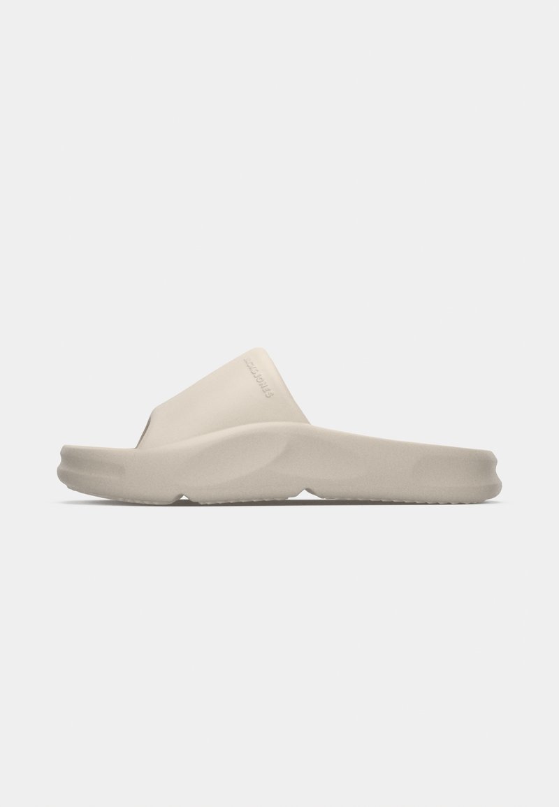 Beige slide sandal with a smooth, matte finish, featuring a wide strap and slightly contoured sole for comfort and stability.