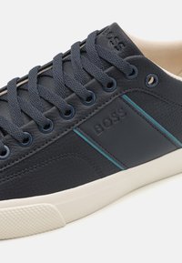 Marine leren sneakers met een gestructureerd oppervlak, contrasterende teal-streep, logo-detail en platte marine sneakers. Crèmekleurige rubberen zool met textuur voor grip.