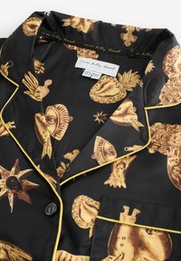 Pijama de satin negru cu modele decorative aurii, având accente aurii și un nasture negru. Include un buzunar cu margine aurie.