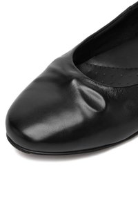 Mustast nahast balleti kingad ümarate varvastega, pehme ja veidi kortsus tekstuur siledal ülemisel osal.