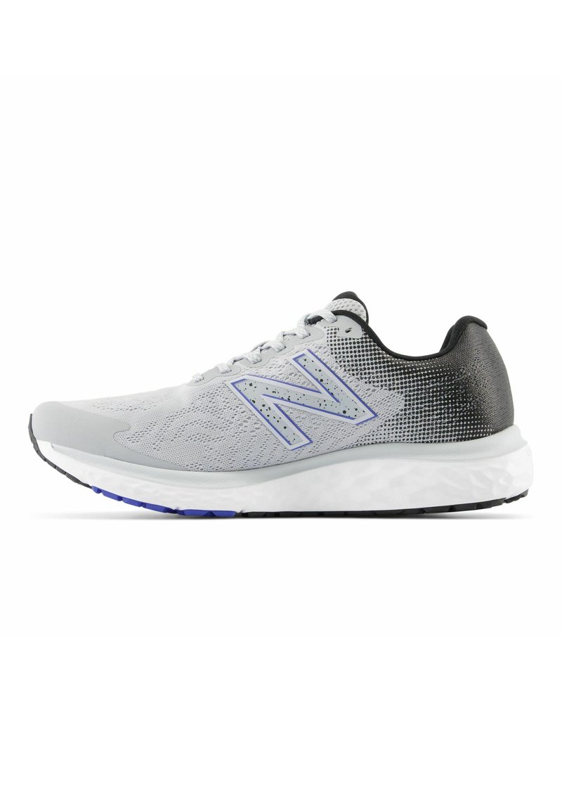 Zapatilla deportiva gris con parte superior de malla, acentos negros, logo "N" prominente, mediopie blanco acolchado y suela de goma negra con detalles azules.