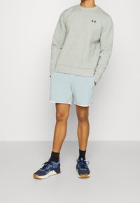 Gray sweatshirt with a crew neckline, light blue shorts with white trim, and blue athletic shoes with textured fabric and gum soles.