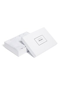 Vit rektangulär låda med ett lock som visar etiketten "Votary." Inuti är flera små vita handdukar noggrant ordnade.