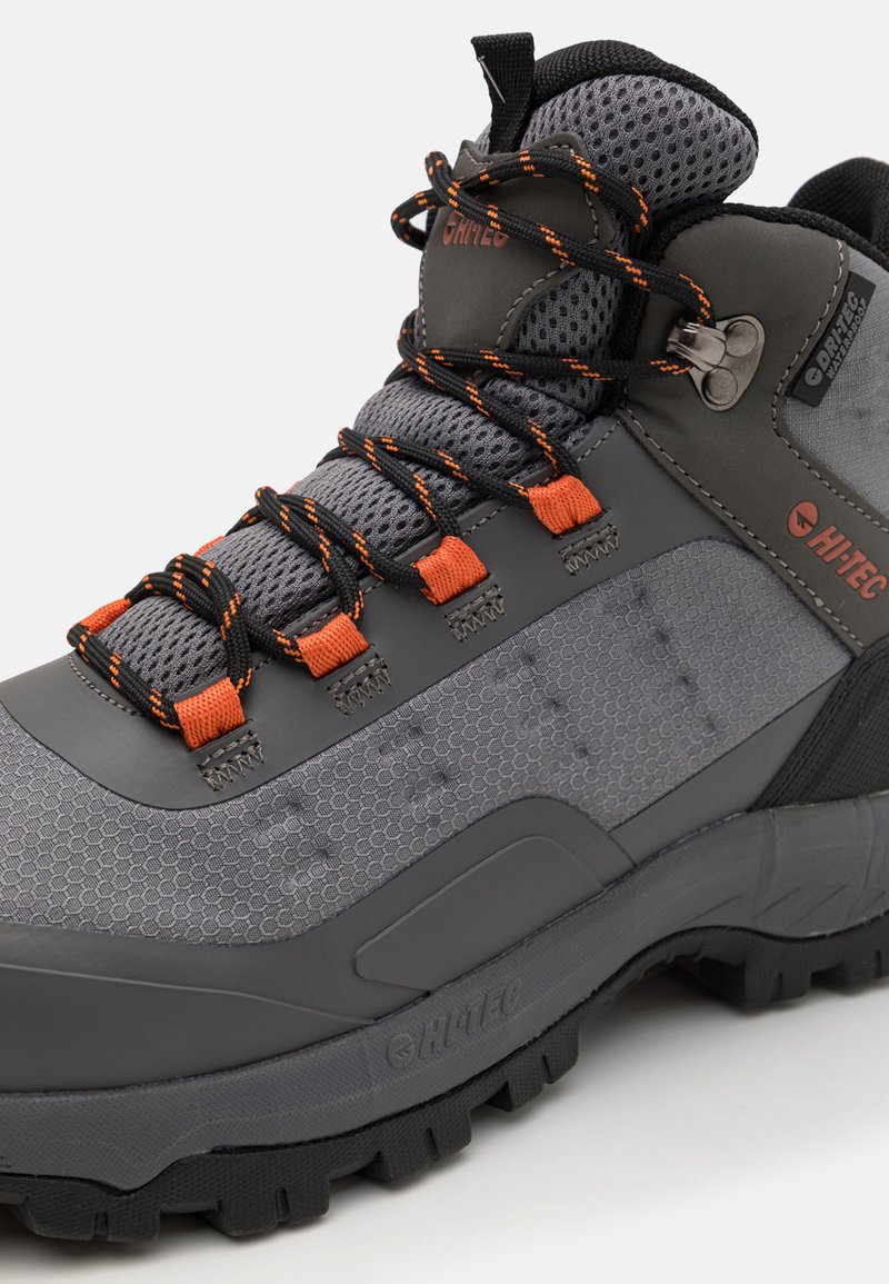 Szare buty trekkingowe z pomarańczowymi akcentami, teksturowana syntetyczna cholewka, wyściełany siatkowy kołnierz i wytrzymała czarna gumowa podeszwa dla lepszej przyczepności.