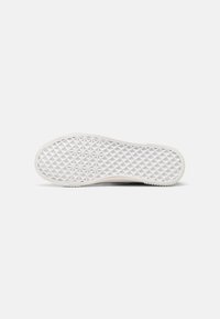 Semelle de chaussure blanche présentant un design de grip texturé en motif diamantaire. La semelle a des bords arrondis et une finition lisse et propre.
