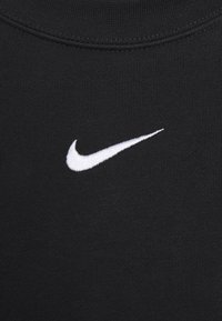Black fabric t-shirt with a ribbed neckline and a small white embroidered Nike logo on the front, featuring a smooth, even texture.