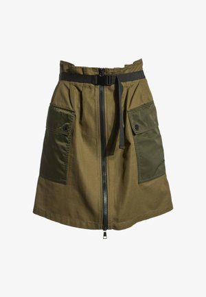 Jupe vert olive avec grandes poches avant, une fermeture éclair centrale et une ceinture noire réglable à la taille.