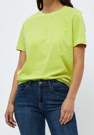 T-shirt en coton vert lime à manches courtes, col rond et coupe décontractée, associé à un jean en denim bleu foncé.