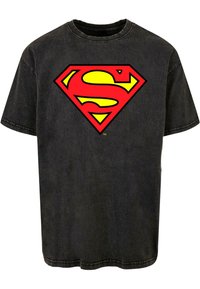 Camiseta de algodón negra con un gran logo de Superman en rojo y amarillo, con cuello redondo y mangas cortas. Textura desgastada visible.