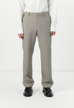 Pantalon à carreaux gris avec une coupe droite, présentant un motif à carreaux subtil et une texture lisse. Porté avec une chemise blanche et des chaussures noires.