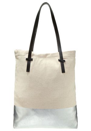 Beige Leinwand-Tragetasche mit silbernem Bodenpaneel und schwarzen Leder-Schulterriemen auf weißem Hintergrund.