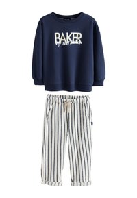Marineblauwe sweatshirt met "BAKER" logo, gecombineerd met wit en marineblauw gestreepte broek met een trekkoord in de taille en opgerolde boorden.