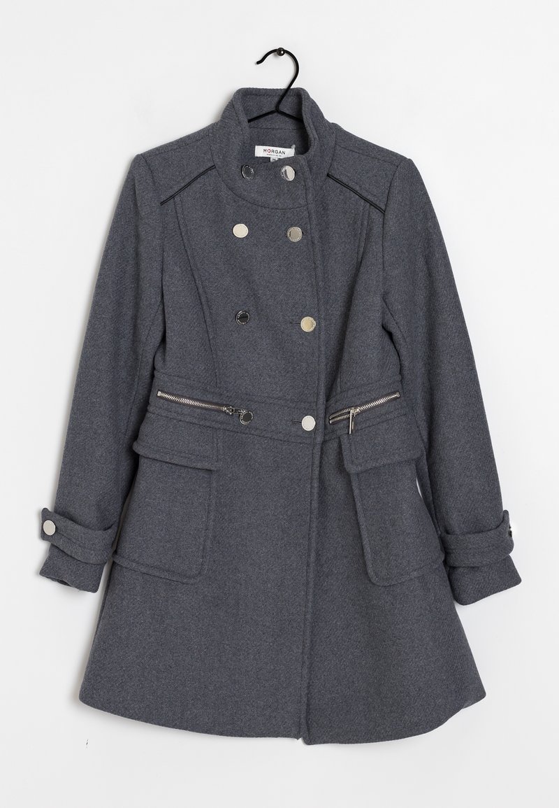 Grå uldfrakke med dobbeltradet design, sølvknapper, flade lommer og justerbare manchetter. Har en lynlåsdetaile ved taljen.