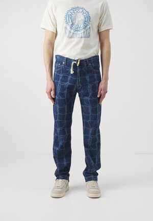 Mørkeblå denimjeans med et lyseblåt geometrisk mønster. Har snøre i livet, standard lommer og lige ben.