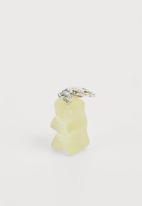 Gul gummibjörn charm gjort av genomskinligt material, med en silverklämma för fäste. Slät yta med tydliga detaljer.
