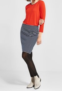 Red long-sleeve top, navy and white striped pencil skirt, black tights, and grey ankle boots with a low heel.