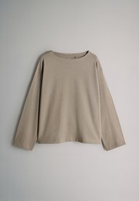 Camiseta de manga larga color beige hecha de algodón suave. Cuenta con un escote ancho, hombros caídos y un ajuste relajado con dobladillo recto.