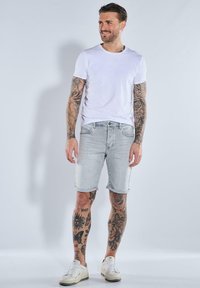 Light gray denim shorts with a regular fit, cuffed hem, and five-pocket design, paired with a plain white t-shirt and white sneakers.