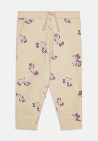 Pantaloni della tuta giallo chiaro con un motivo ripetuto di unicorni in rosa e viola. Presentano una vita elastica e fondo gamba a costine.